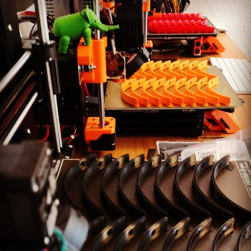 Une série de pièces orange en production sur une imprimante Prusa